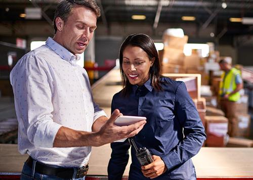 Woman and man standing in a warehouse looking at a tablet